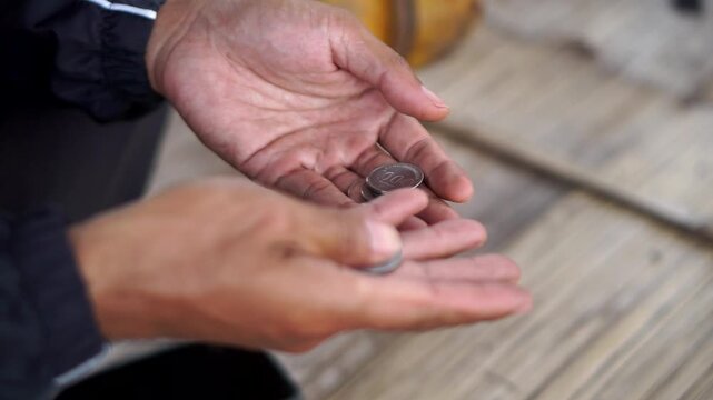 Detailed footage of a man's hands sorting and counting rupiah coins as an illustration of daily finances.