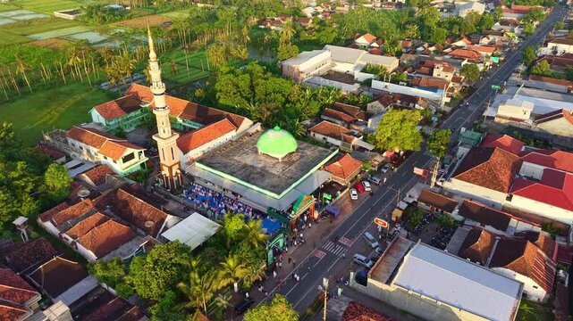 Aerial view of mosque with people gathering for prayer, Islamic worship, community activity, urban Indonesia, religious scene.