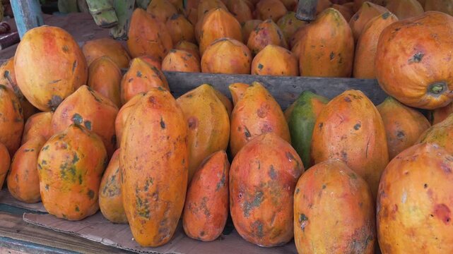 Large pile of fresh orange papayas on display for sale at local street market