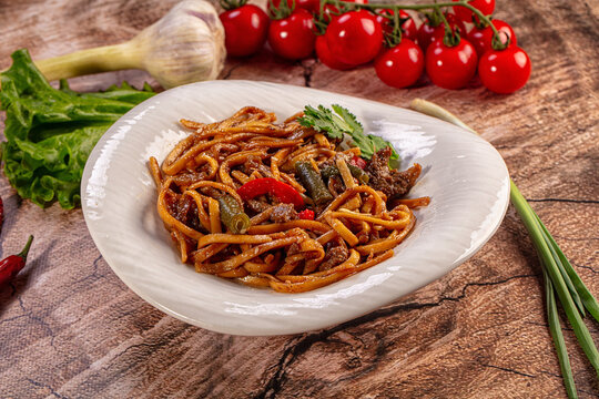 Savory stir fried noodles with beef and vegetables on a rustic wooden table
