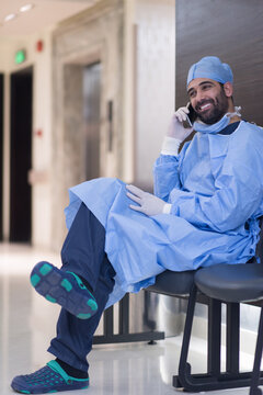 Smiling surgeon in scrubs taking a phone call outside a modern eye hospital clinic in Egypt