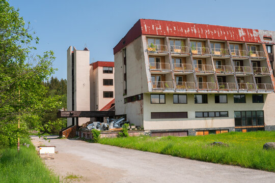 View of the abandoned hotel Junior in Krpacovo with its decaying facade and overgrown balconies under a clear blue sky in Dolna Lehota, Banskobystricky kraj, Slovakia.