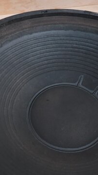 A large black paper subwoofer cone vibrates intensely while playing low-frequency bass. The ribbed texture of the acoustic speaker moves rapidly to create strong sound pressure.
