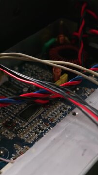 Intricate windings of a toroidal inductor and colorful wires on a blue printed circuit board. Concept of electronics, engineering, technology, and complex systems.