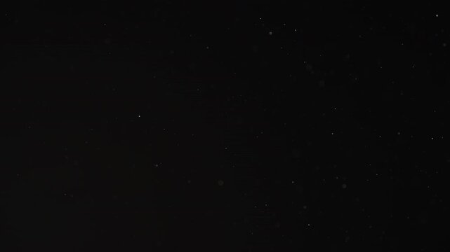 Slow motion real dust particles floating mid air over dark background