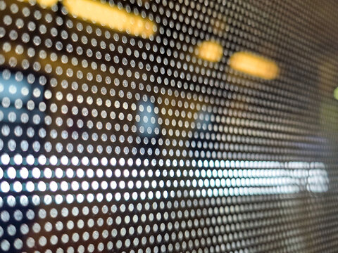 Close up view of perforated window film showing mysterious abstract pattern of dot matrix hole detail with blurred light shining through creating calm and intriguing bokeh effect background