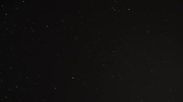 Slow motion real dust particles floating mid air over dark background