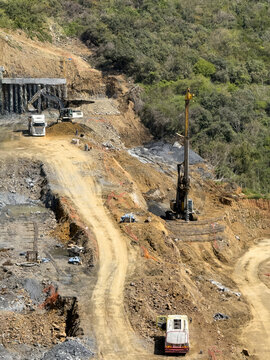 View of heavy machinery including an excavator and a drilling rig working on a construction site carved into a lush green hillside Sariyer, Istanbul, Turkey.