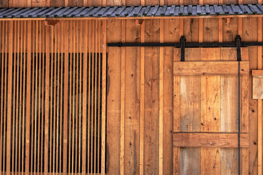 Contemporary fusion of styles - Japanese building incorporating traditional cedar timber, wooden slats, and corrugated eaves with modern barn-style sliding doors and minimalistic ornamentation.