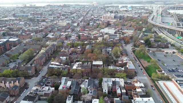 Highway corridor view neighborhood near MLK Jr Blvd shows brick housing blocks beside elevated ramps leading toward industrial waterfront. Mixed roofing define compact textures Baltimore, MD