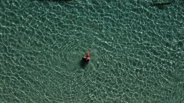 Romantic playful couple on summer vacation, enjoying turquoise sea water swim, Greek Island, Paros, Overhead aerial