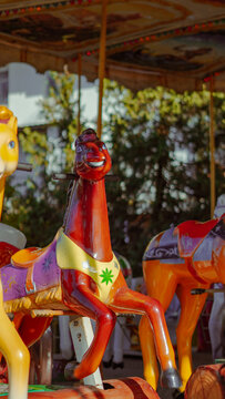 A glossy brown carousel horse with a purple saddle at an amusement park
