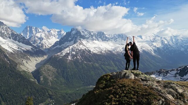 Romantic couple celebrating on an alpine summit above the Mer de Glace valley in Chamonix, France, with snowy mountains in the background, captured in cinematic slow motion
