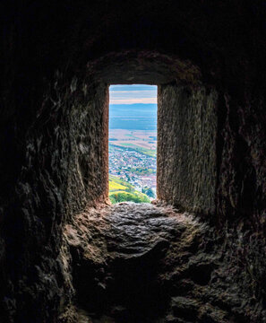 View of Ribeauville town and Alsace valley through dark stone window of medieval castle. Framed landscape from Saint Ulrich fortress ruins during autumn in France.