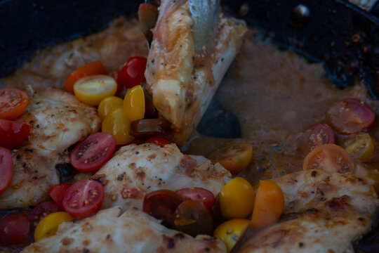View of chicken fillets cooking in a pan with fresh cherry tomatoes and savory sauce Moab, Utah, United States.