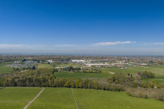 Aerial panorama of the Harrogate Showground in North Yorkshire England with exhibition buildings parking areas countryside fields and suburban landscape beneath a blue sky with a few clouds