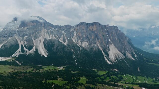 Wide aerial view of Seceda ridge and Dolomites cliffs. Mountain landscape under cloudy sky and fog