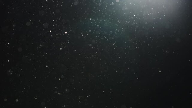 Slow motion real dust particles floating mid air over dark background