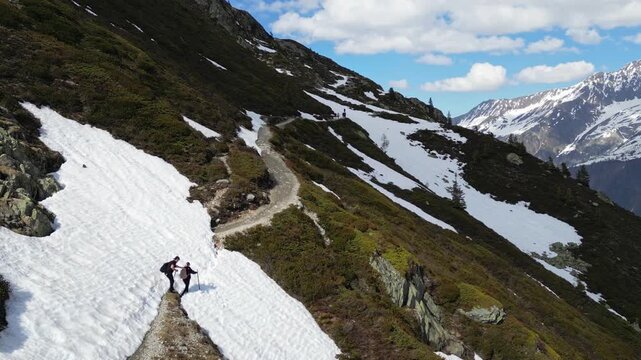Snow hikers crossing a scenic alpine trail near Lac Blanc in Chamonix, France, surrounded by snowy peaks and dramatic mountain landscapes in the French Alps.
