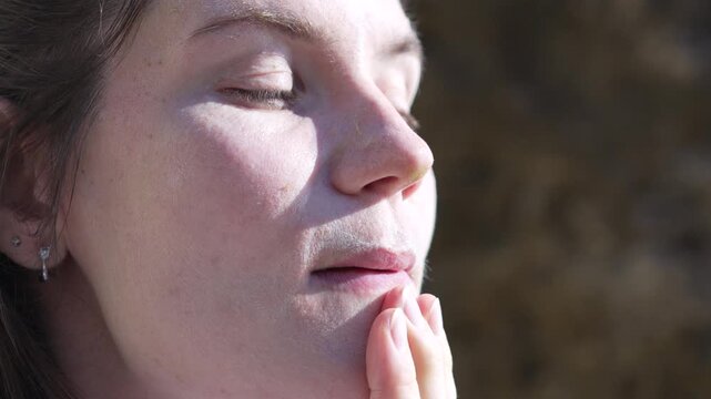 Woman meditation skincare close up shot of a peaceful woman with closed eyes touching her face during a serene outdoor meditation session