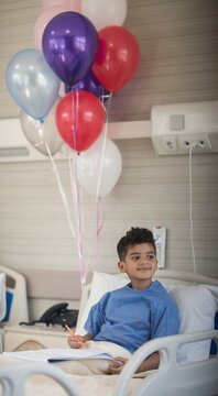 Smiling young patient in hospital bed with balloons after eye surgery at a modern clinic in Egypt