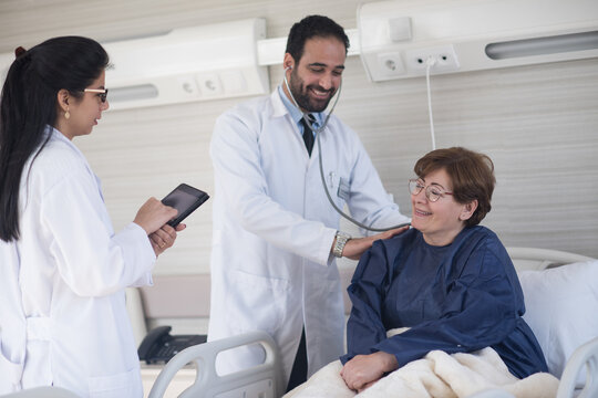 Doctors examining a smiling eye patient during a consultation at a modern Middle Eastern eye hospital clinic in Egypt