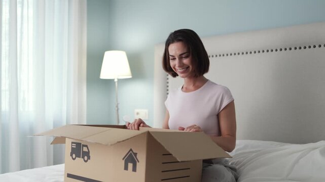 Woman sitting with delivery box and starting unboxing process. Concept online shopping, ecommerce and parcel delivery.
