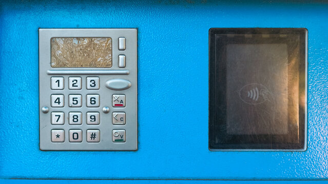 A blue payment terminal with a silver keypad and a contactless reader