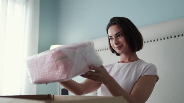Happy woman carefully examining contents of opened package. Concept online shopping, delivery and customer satisfaction.
