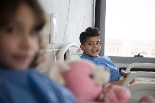 Smiling boy resting in a pediatric eye hospital bed at a modern clinic in Egypt with plush toy