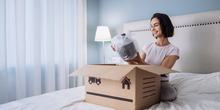 Young woman reviewing delivered product at home after online shopping. Concept ecommerce lifestyle and retail experience.
