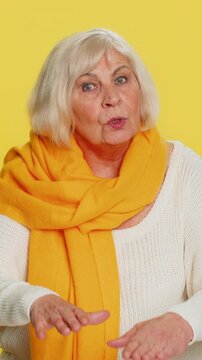 Hey you, be careful. Strict senior woman warning with admonishing hands gesture, saying no be careful scolding, giving advice to avoid danger disapproval sign. Grandmother on yellow studio background