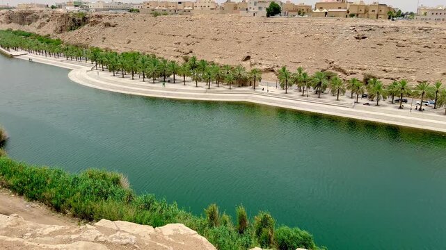 High angle panoramic view of Wadi Hanifa in Riyadh with palm trees and water canal.