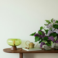 Fototapeta premium A serene interior with a modern green lamp, watering can, and fresh purple flowers on a wooden console table