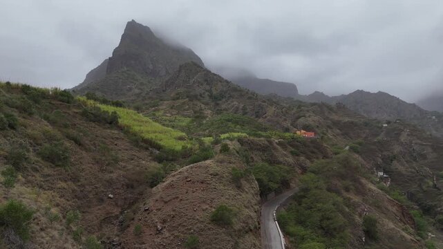 Aerial drone view of the lush, jagged mountain peaks of Santo Antao, Cabo Verde. Low clouds brush against the volcanic ridges and terraced slopes of this remote hiking paradise in Cape Verde