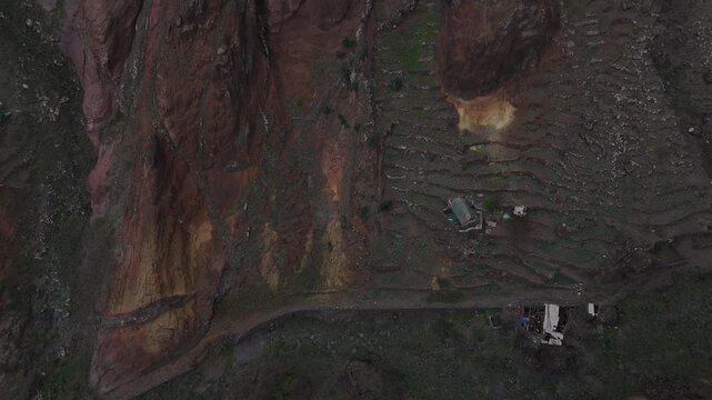 Aerial drone view looking down into a deep, lush canyon in the volcanic mountains of Santo Antao, Cabo Verde. Terraced agriculture and steep ridges define this unique trekking landscape