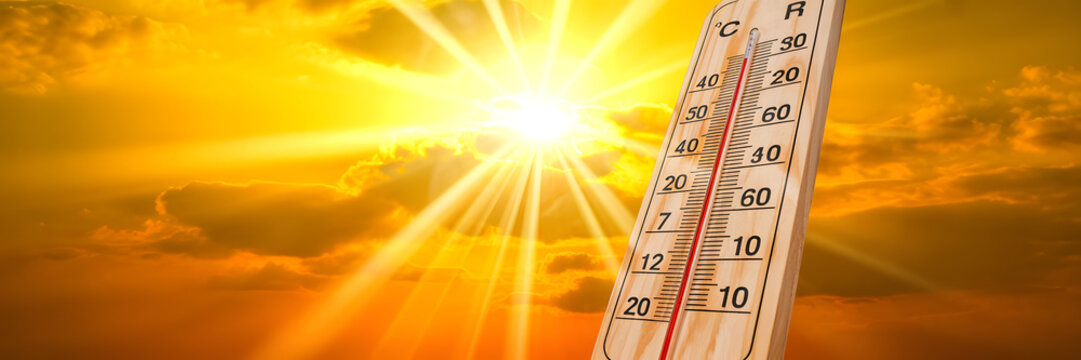 Thermometer measuring extreme heat under a bright sun with radiant rays and clouds
