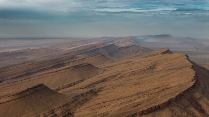 Aerial view of dramatic desert mountain ridge with layered rock formations and telecommunication towers, arid landscape Morocco © Qisse