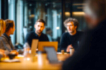 Fototapeta premium Blurred Professionals engaged in a dynamic business meeting with laptops