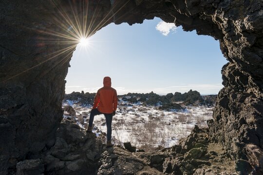 Man in a rock arch with sunbeams, volcanic landscape, volcanic area Krafla, Dimmuborgir National Park, M&yacute;vatn, Iceland