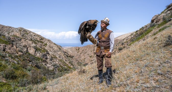 Traditional Kyrgyz eagle hunter with eagle in the mountains, hunting, near Bokonbayevo, Issyk Kul region, Kyrgyzstan