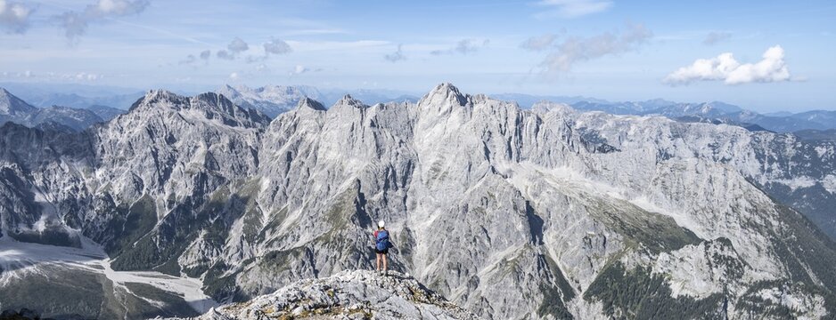 Hiker with helmet looking at mountains, Hochkalterstock mountain range with Blaueisspitze and Hochkalter, hiking trail to Watzmann, Watzmann crossing, Berchtesgaden, Bavaria, Germany