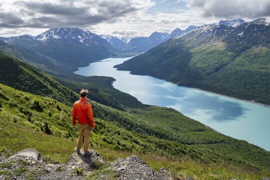 Mountaineer enjoys views of blue lake and mountains on Twin Peaks Trail, Eklutna Lake, Chugach Mountains, Chugach State Park, Alaska, USA