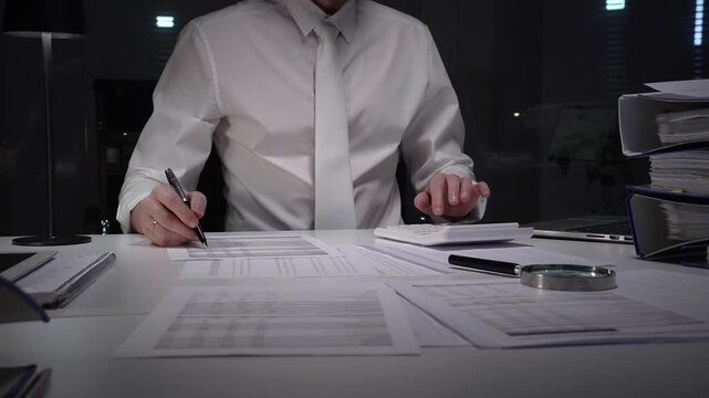 Business professional working late on financial audit in modern office, analyzing tax documents and managing paperwork deadlines with precision and expertise