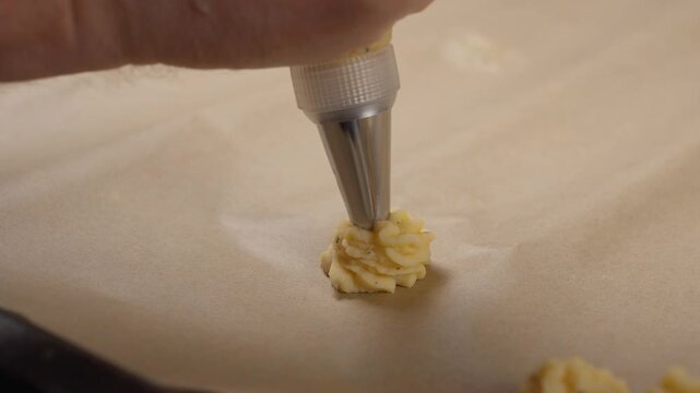 Squeezing white cream from a pastry bag close up shot