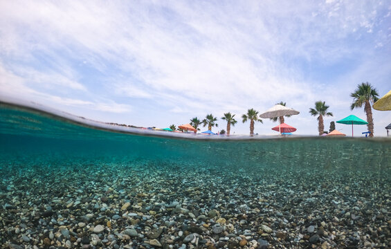 Split-level pebble beach with colorful umbrellas and palms