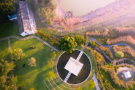 Aerial view of a modern pavilion in a circular pond surrounded by lush green lawns and stone pathways in Cape Town, Western Cape, South Africa.