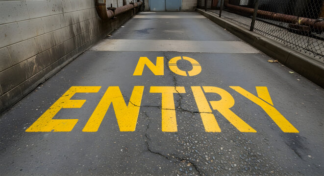Yellow No Entry text painted on asphalt ground of an industrial alleyway