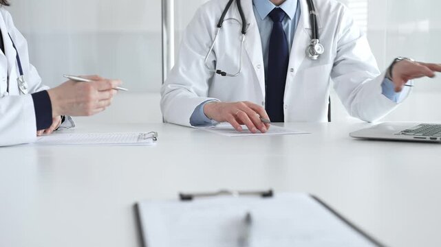 Medical team working at bright clinic table, doctors reviewing patient files, discussing healthcare diagnosis, clinic meeting. Medical team meeting