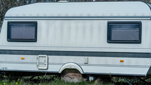 Old caravan trailer side featuring windows and weathered textures. Reflects long term parking, holiday, and road trip concepts